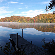 Adirondack Lake with a dock and orange and yellow trees 