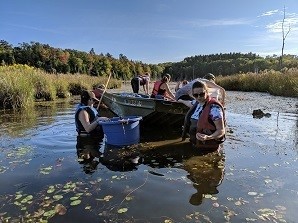 Volunteers in boat cleaning up invasive species from water