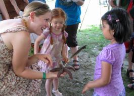 A young woman holds a live sea star while two children watch.