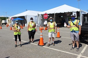 4 workers holding up test kits at a coronavirus test site
