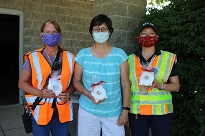 Regional director poses with 2 others as they hold up coronavirus test kits