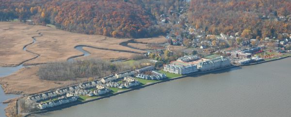 An aerial view of several apartment complexes at the edge of a river surrounded by a tidal marsh