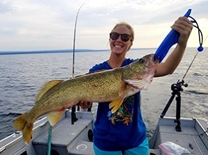 Woman holding a fish she caught while on a boat