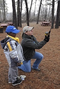 Woman teaching a young boy how to fish