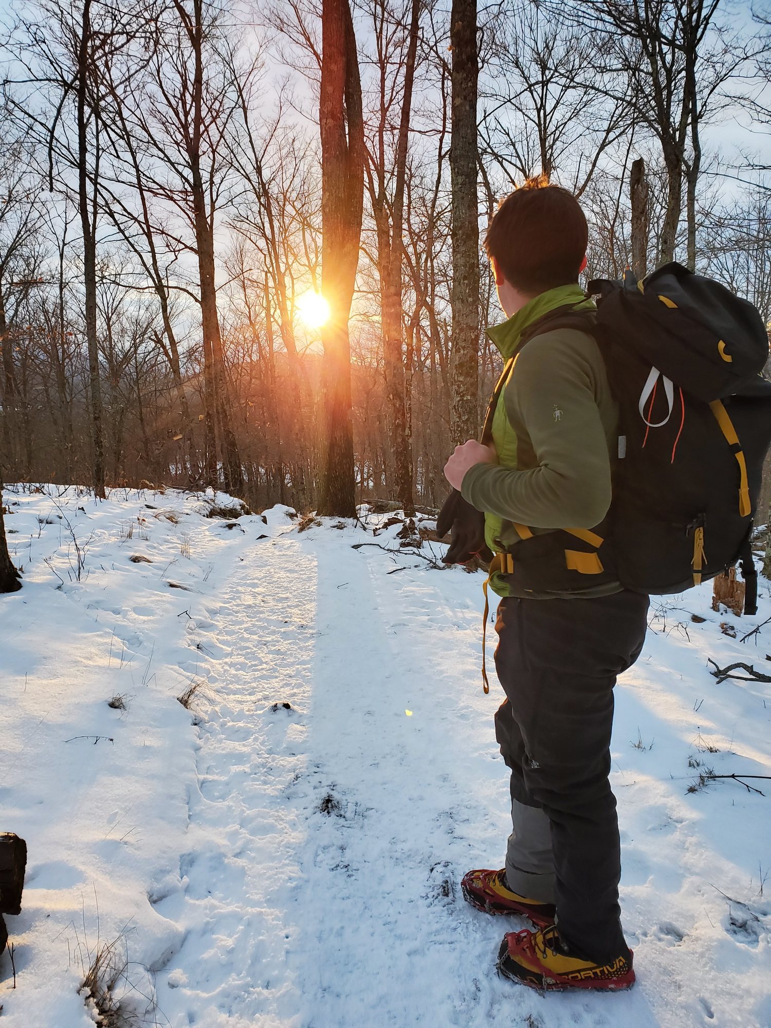 Hiker on snowy trail at sunset