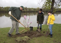 School children standing by the edge of the Hudson River learning how to plant a tree