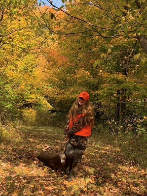 Young woman dragging harvested buck in forest clearing