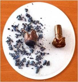 hundreds of small fragments of a lead slug, next to the two intact halves of a copper slug to depict comparison