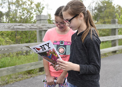 Two children reading a booklet that says I Bird NY on the front cover with a blue jay