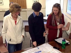 Three adults study a map of Orange County natural resources. 