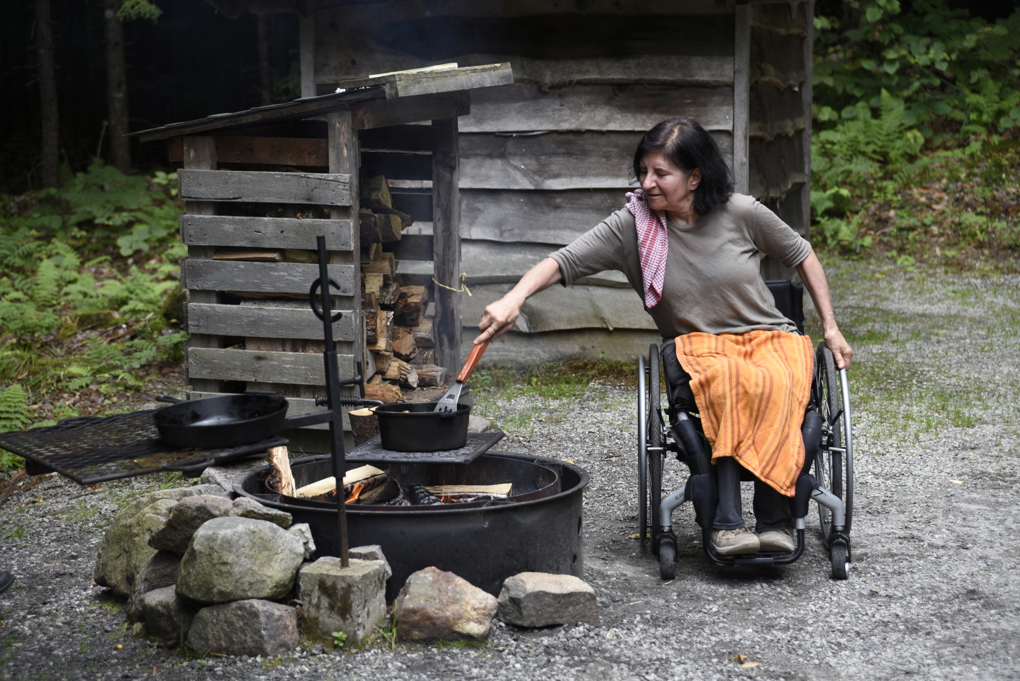 Woman in wheelchair cooking over accessible campfire pit