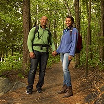 A couple smiling as they are hiking through the woods
