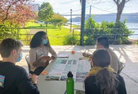 4 people sit around a table looking at maps near the Hudson River in Poughkeepsie.