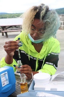 A young woman uses a test tube to examine drops of water.