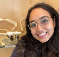 A young woman wearing glasses next to a display of fish skeletons.