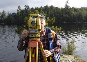 a man using surveying tools by a lake