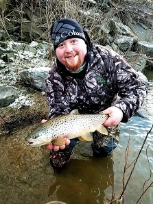Charles Wlasniewski holding up Brown Trout in stream