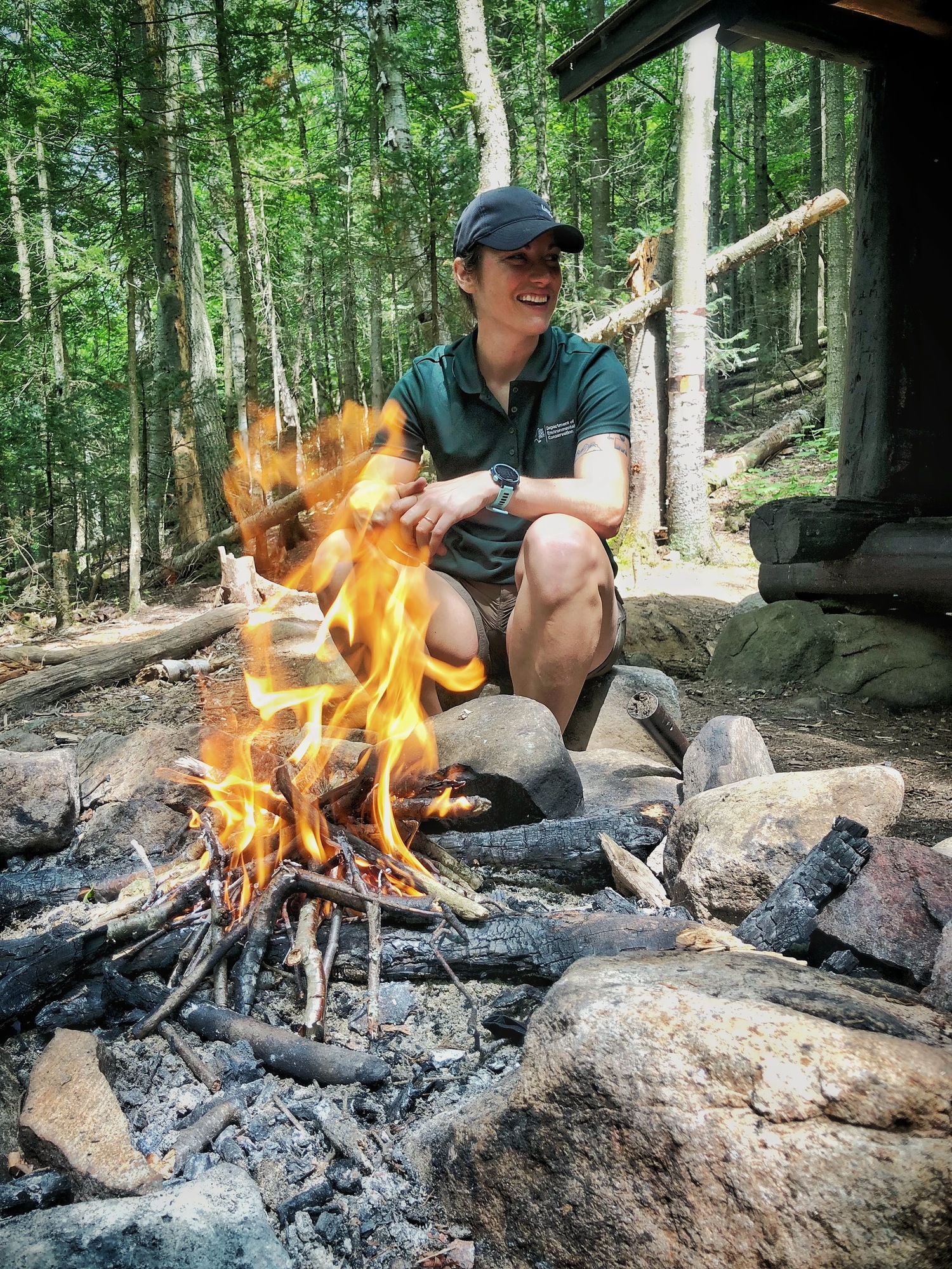 DEC employee sitting at campfire