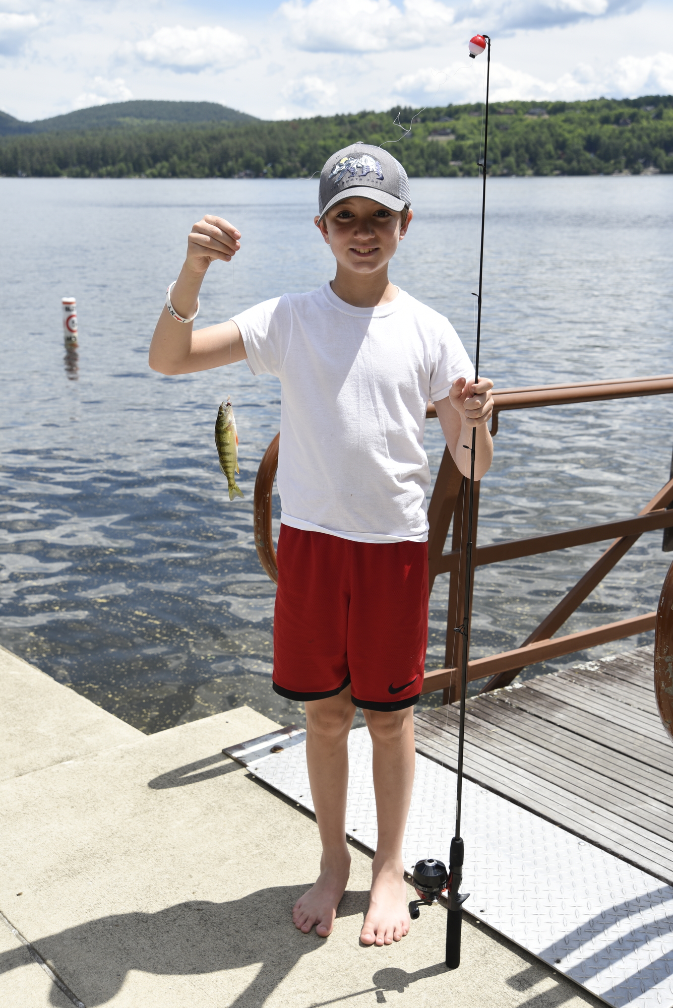 Boy standing on dock with fish he caught