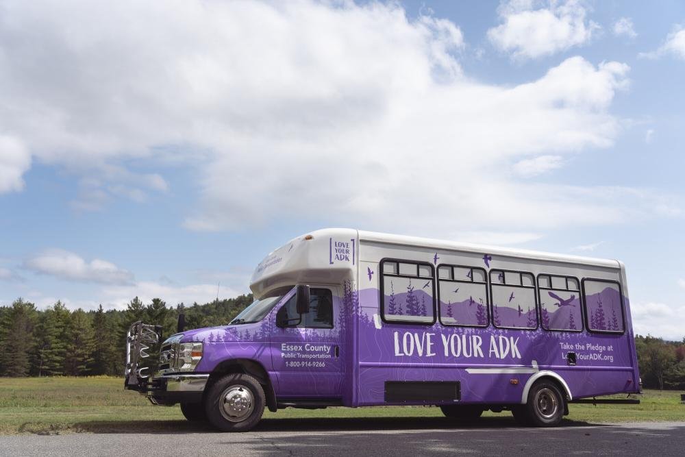 A purple shuttle bus sitting at Marcy Field waiting to pick up hikers