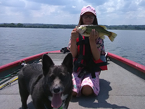 Angler with a bass and her dog.
