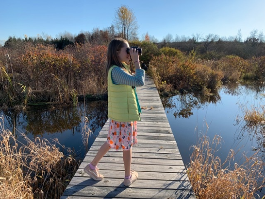 A person birding on a boardwalk