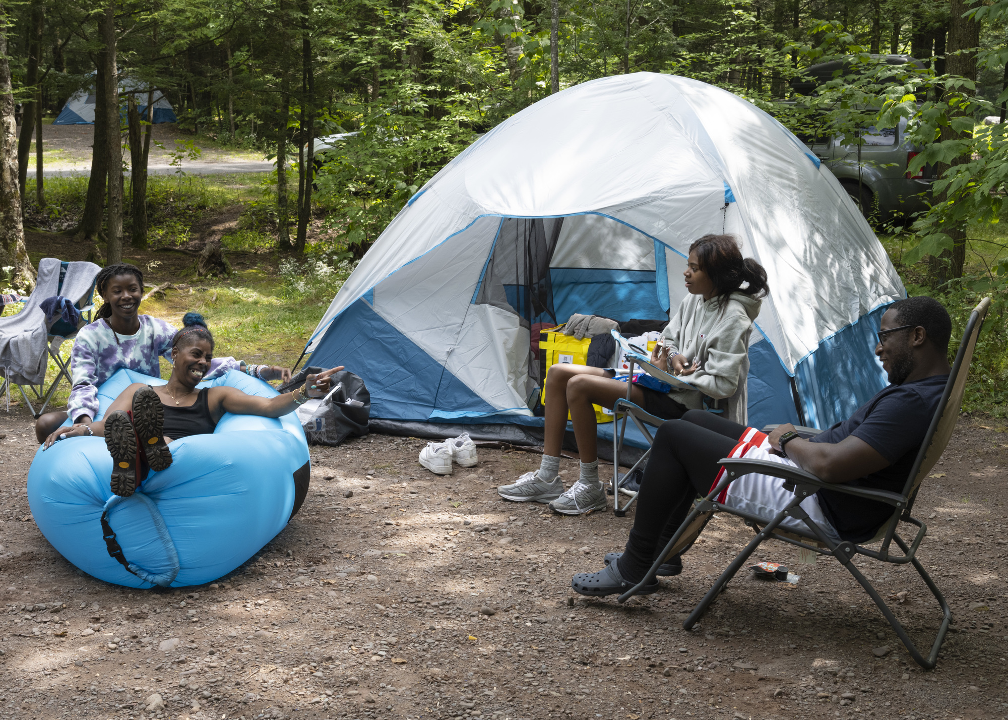 A family sitting around their tent while on a camping trip