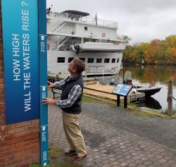 A man looks at a sign showing predicted sea-level rise along the Roundout in Kingston