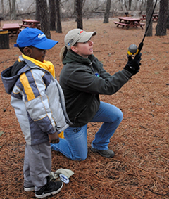 A child learns how to cast a fishing rod at a Free Fishing Day event