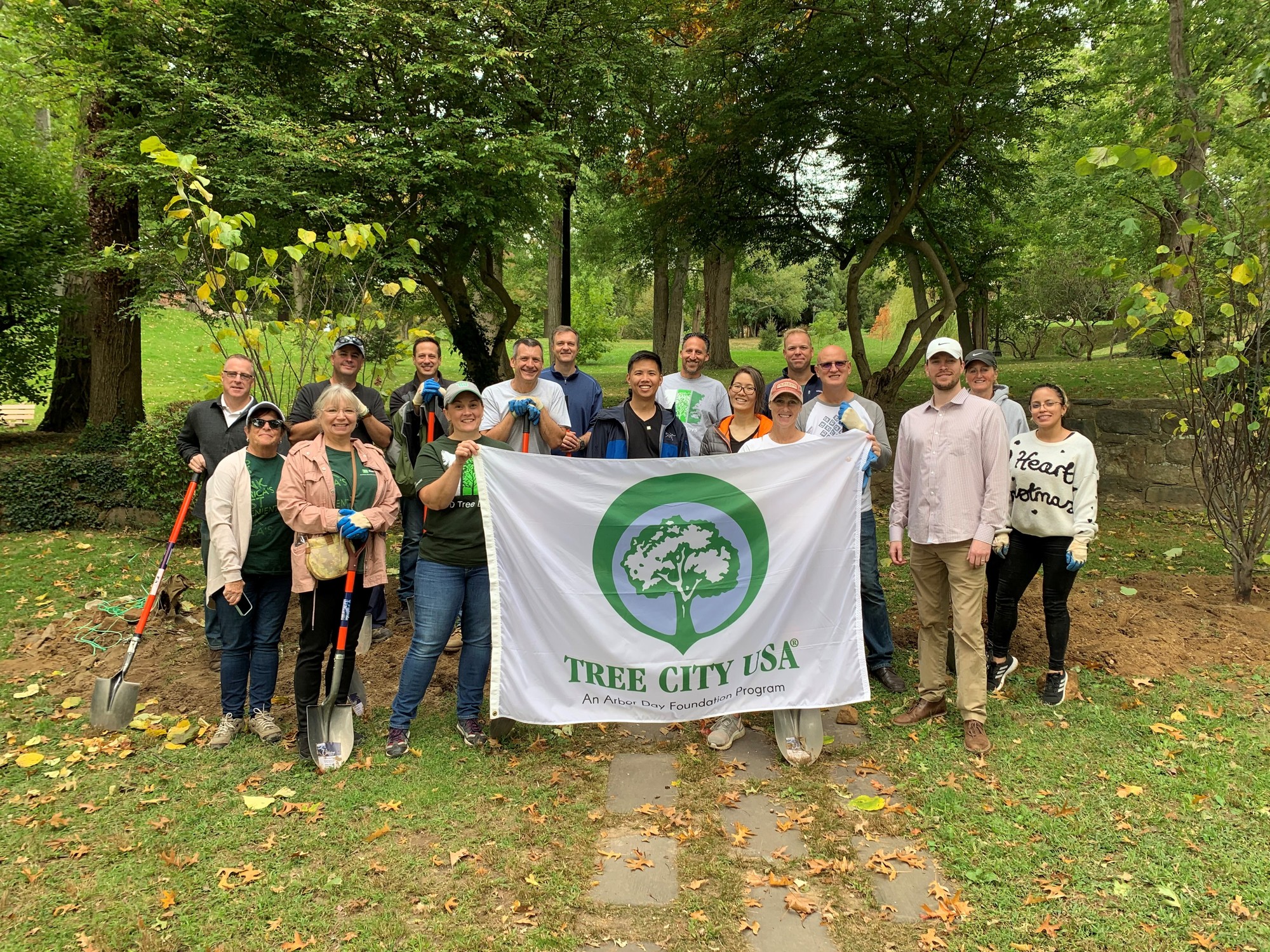 Tree planting volunteers holding shovels and a Tree City USA banner.