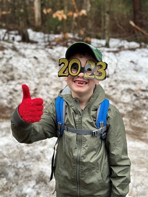 A kid giving a thumbs up on a First Day Hike wearing 2023 glasses