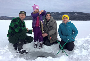 Family ice fishing on a lake