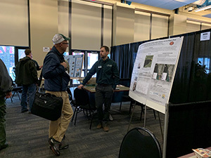 Biologist presenting poster to an interested individual