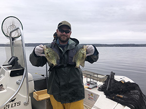 Man holding two black crappies