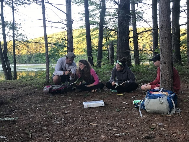 A camp counselor giving campers a lesson in the woods