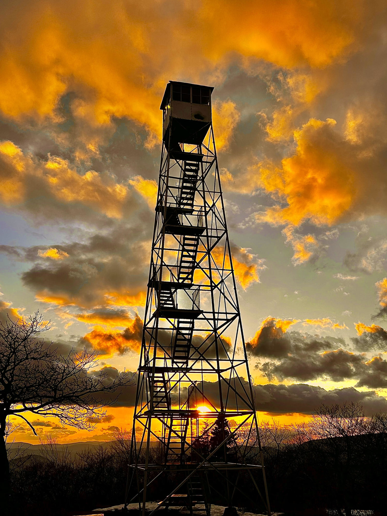 The sun rising behind a fire tower in the Catskills