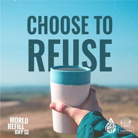 World Refill Day - A person's hand holding a reusable cup with a scenic mountain background