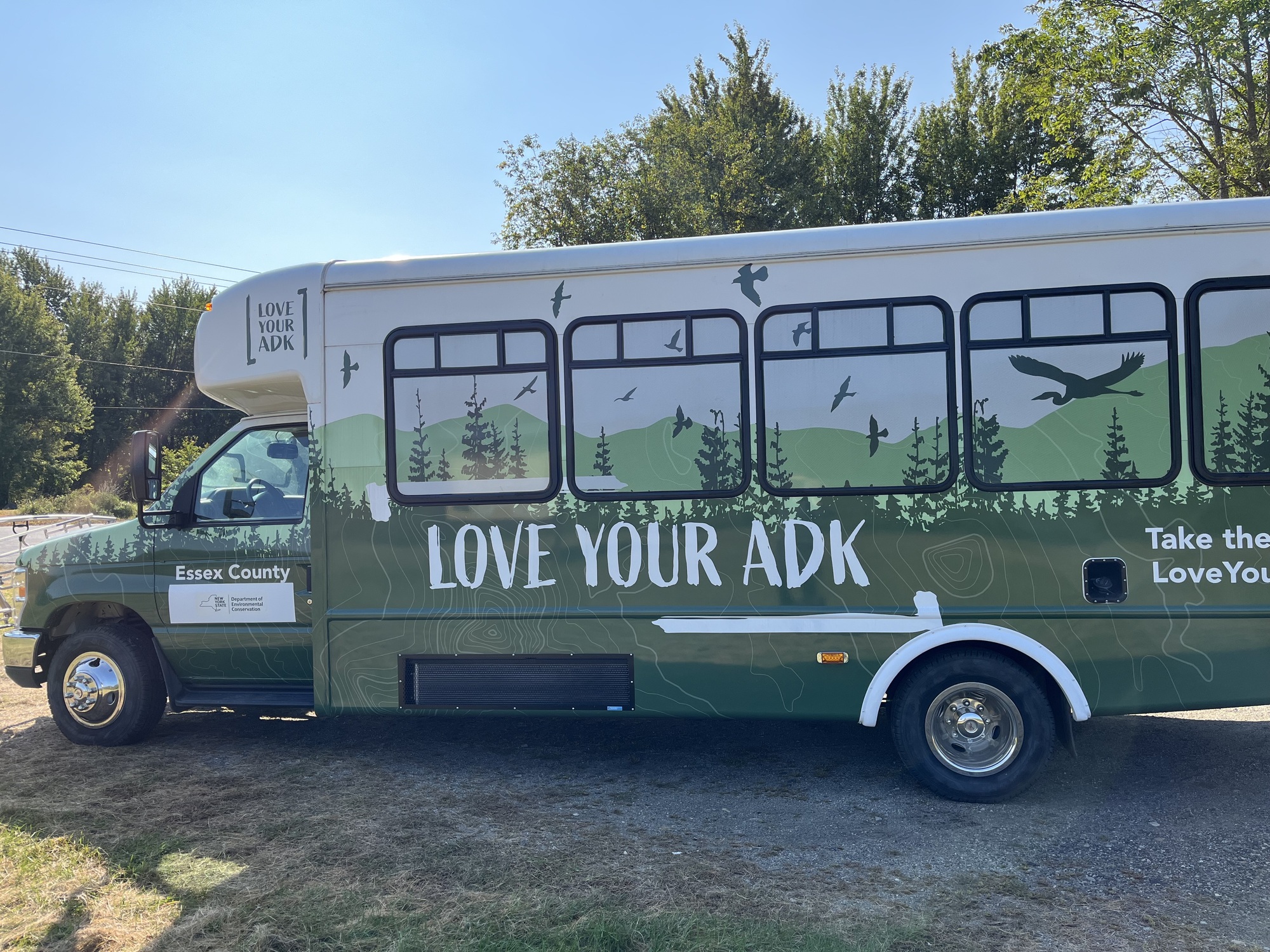 A green shuttle bus that has been converted to a mobile interactive education station. 