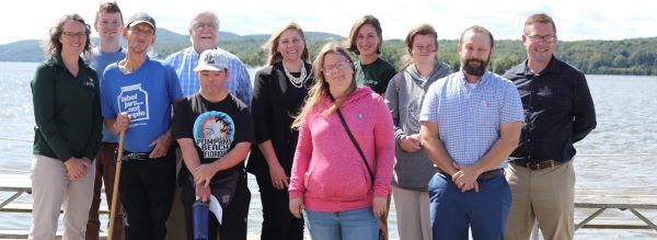 A group of 11 people pose in front of the Hudson River