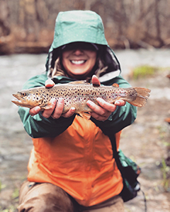 Woman holding a small brown trout.