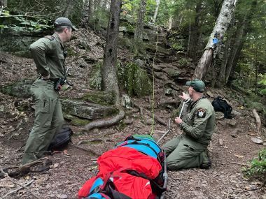 Rangers in woods conducting rescue
