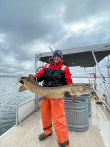 Riley Delpriore, Fish Culturist, holding up a large muskellunge,