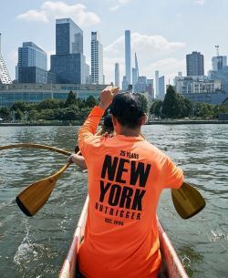 A person in an outrigger canoe with the skyline of NYC 