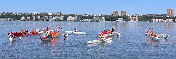 Paddlers in 1-person and 6-person outrigger canoes on the water in New York City