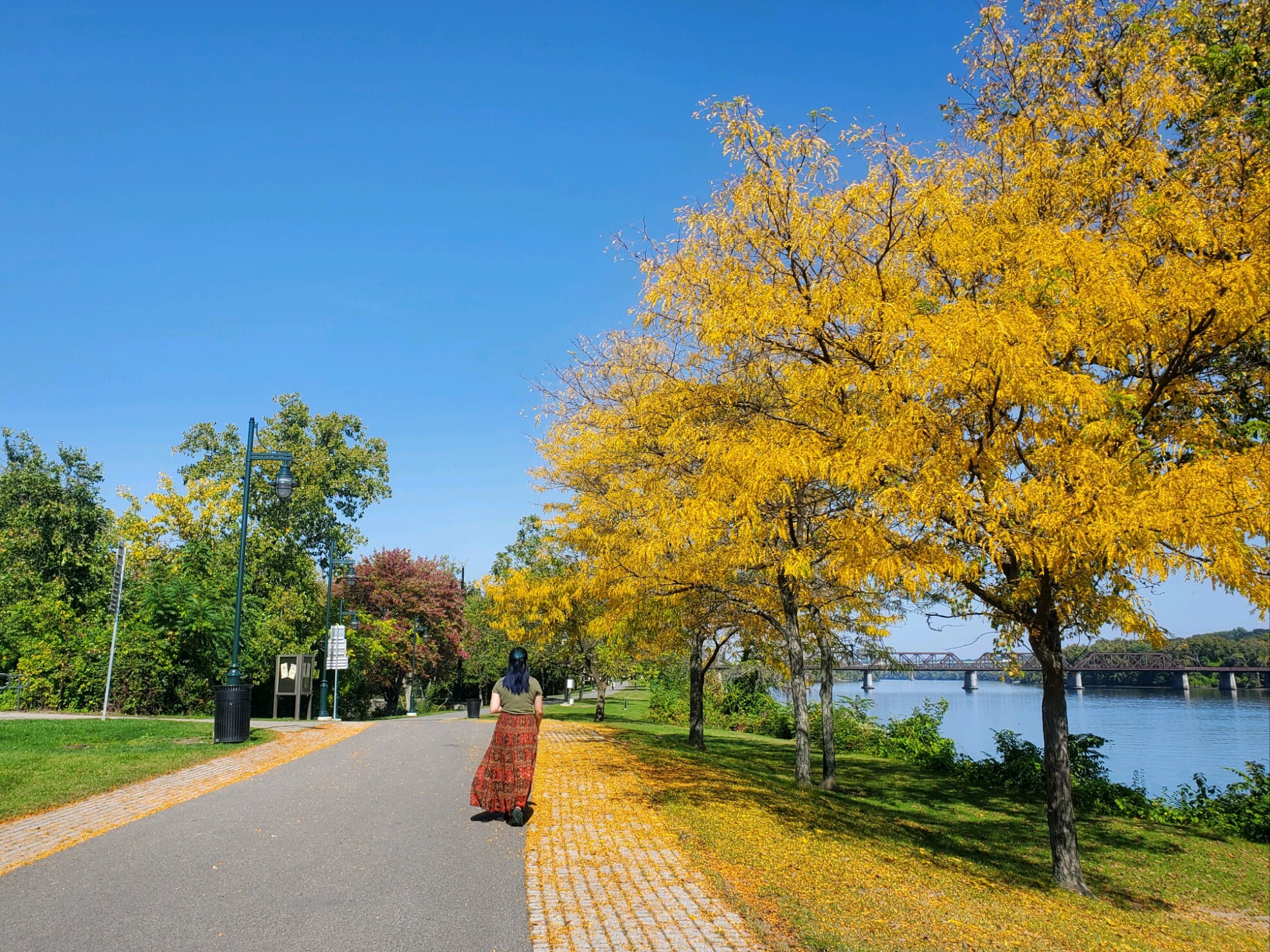 Woman walking through a riverside urban park in fall