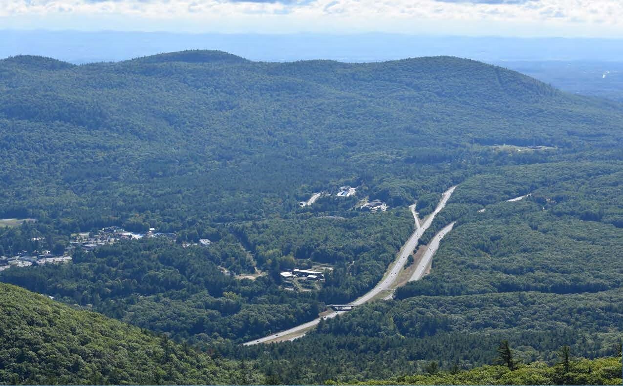 Aerial view of the Adirondacks with centralized roads and buildings surrounded by forested mountains