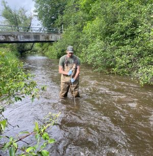 A man in waders in a stream with a net