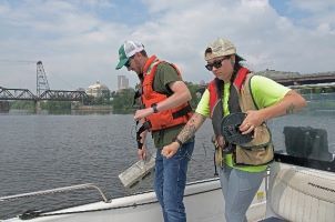 Two people in a boat checking monitoring equipment.