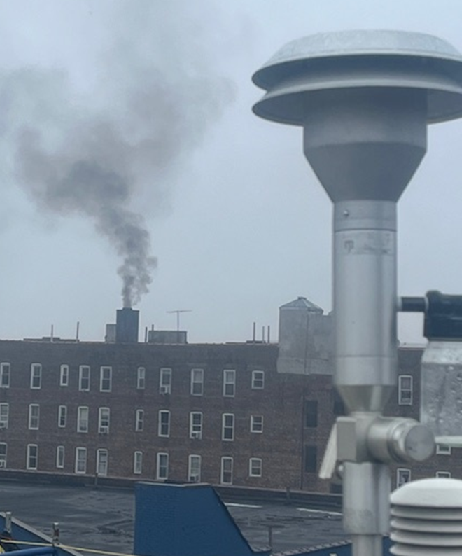 A large building with thick exhaust coming from its chimney.