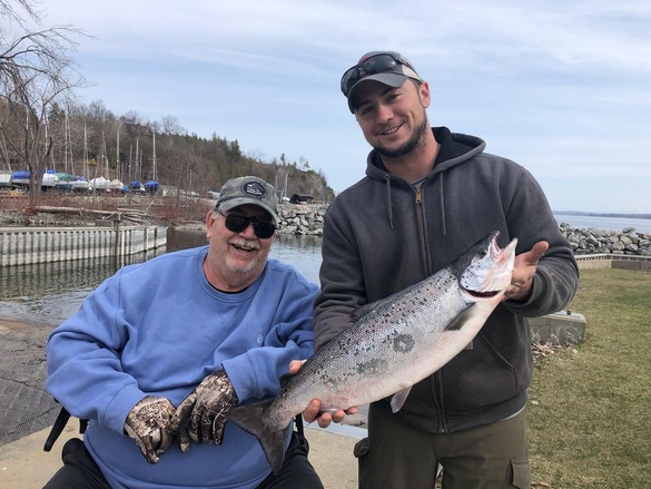 Two angler holding an Atlantic salmon on the shore of Lake Champlain.
